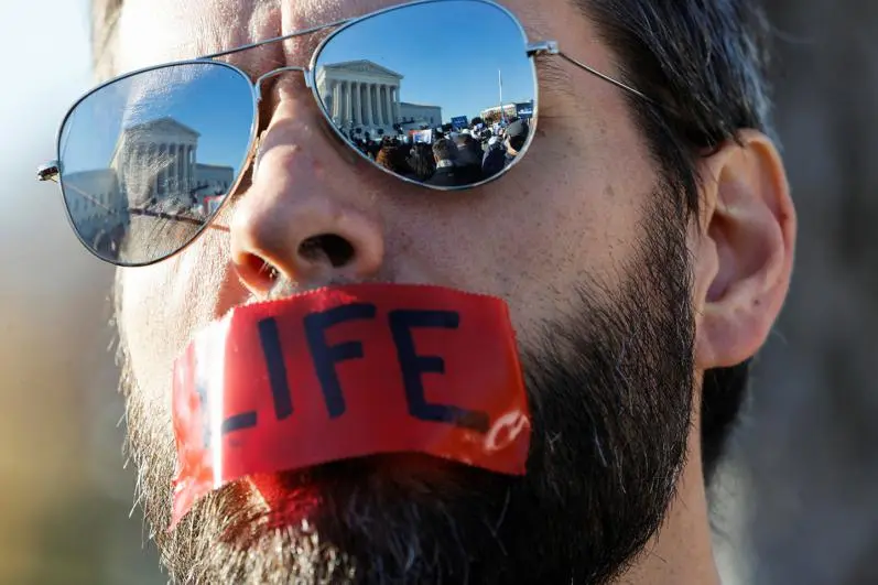 man wearing sunglasses and with tape covered in his mouth with "life" text