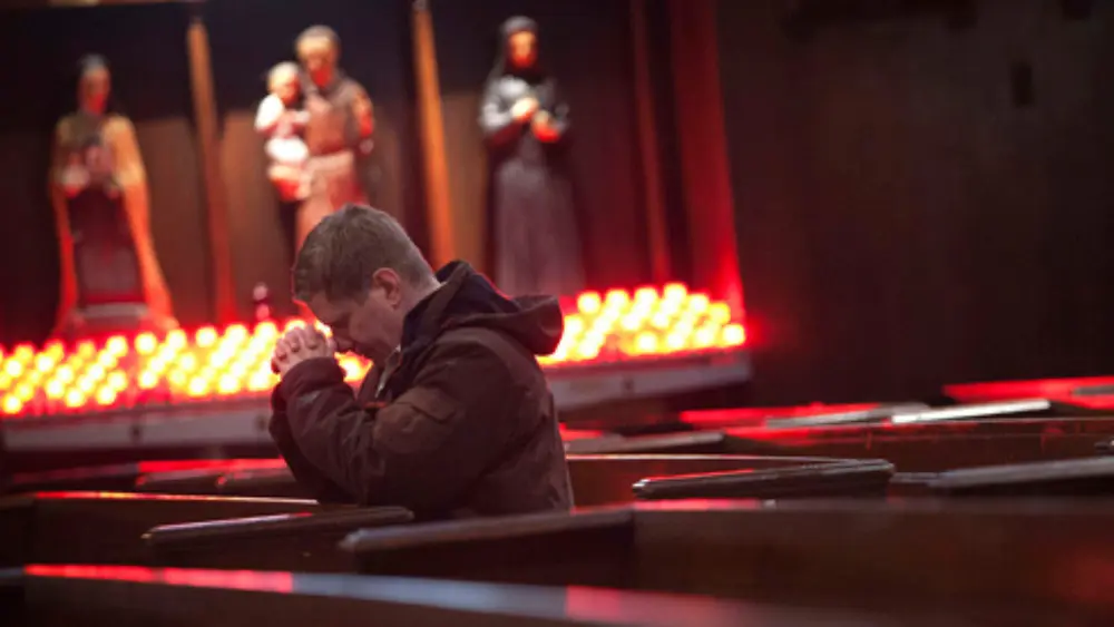man kneeling and praying at church